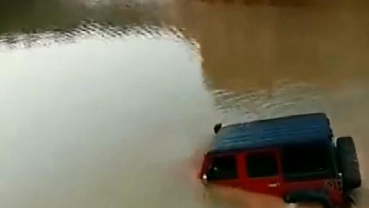 吉普牧人玩越野涉水游戏，他的车有一半浸在水里。
